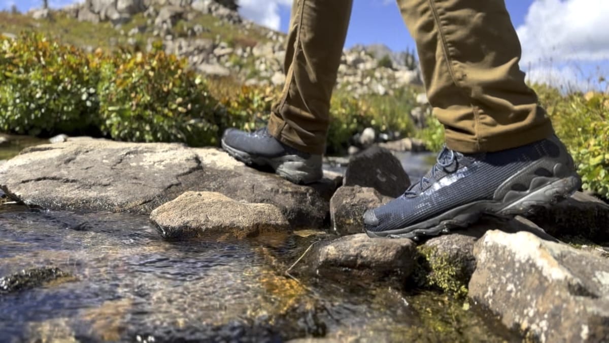 Close up of hikers trail runners crossing a stream on the Four Pass Loop in September.